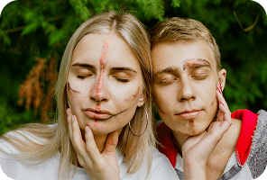 Couple with painted faces in a forest clearing